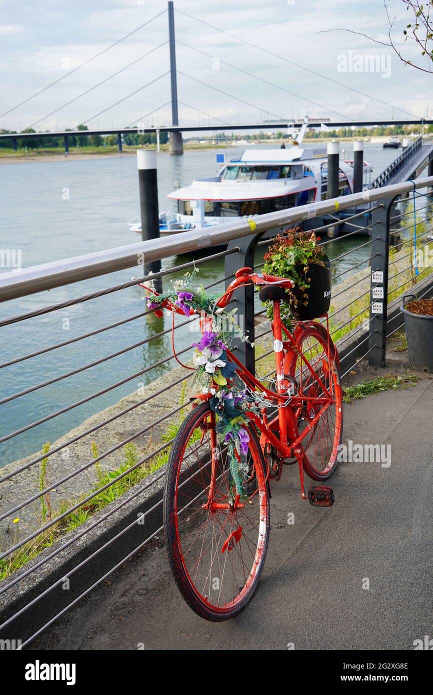 A red decorative bike with flowers in front of the 'Kasematten' restaurant at the Rhine river promenade in Düsseldorf. Stock Photo