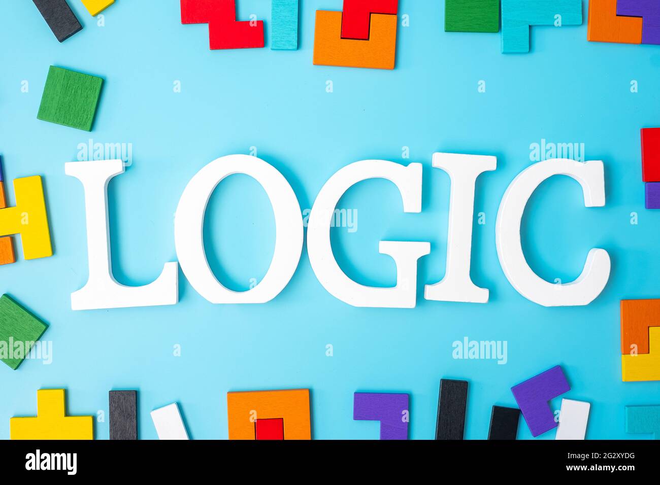 LOGIC text with colorful wood puzzle pieces, geometric shape block on blue background. Concepts of logical thinking, Conundrum, solutions, rational, s Stock Photo