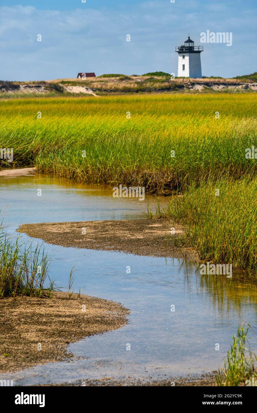 A view of the saltwater marshes with grasslands and Wood End lighthouse afar along the Atlantic Ocean in Provincetown, Cape Cod, Massachusetts. Stock Photo