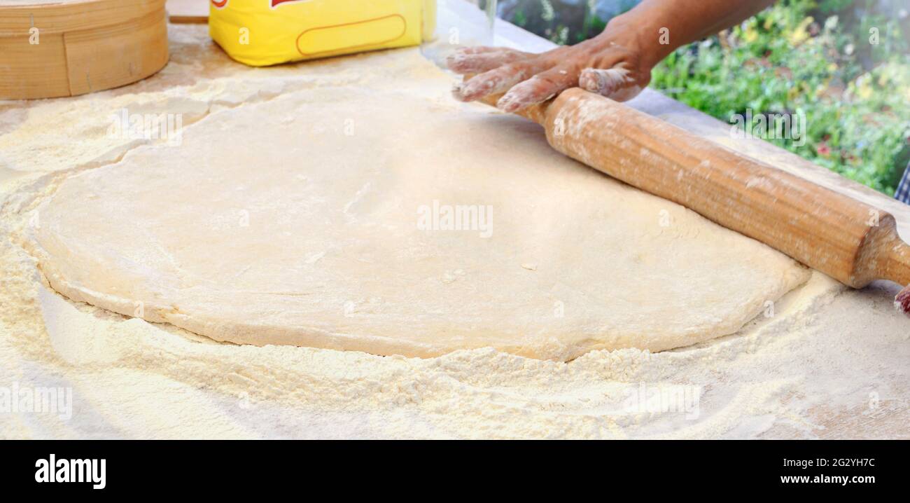 Woman chef rolls out yeast dough with a rolling pin on the table. Copy ...