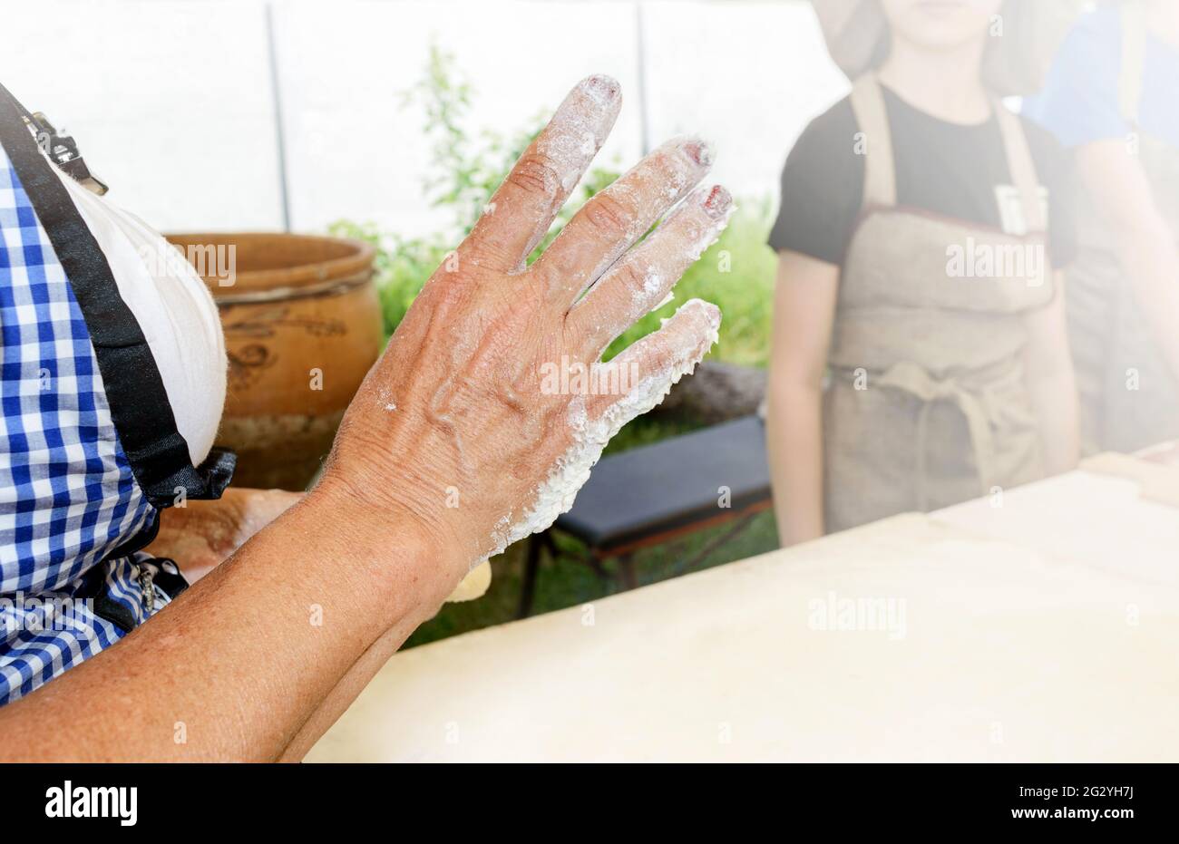 The cook teaches children to making sweet donuts. The female hand in the foreground draws attention. Cooking at home. Master class in baking. Stock Photo