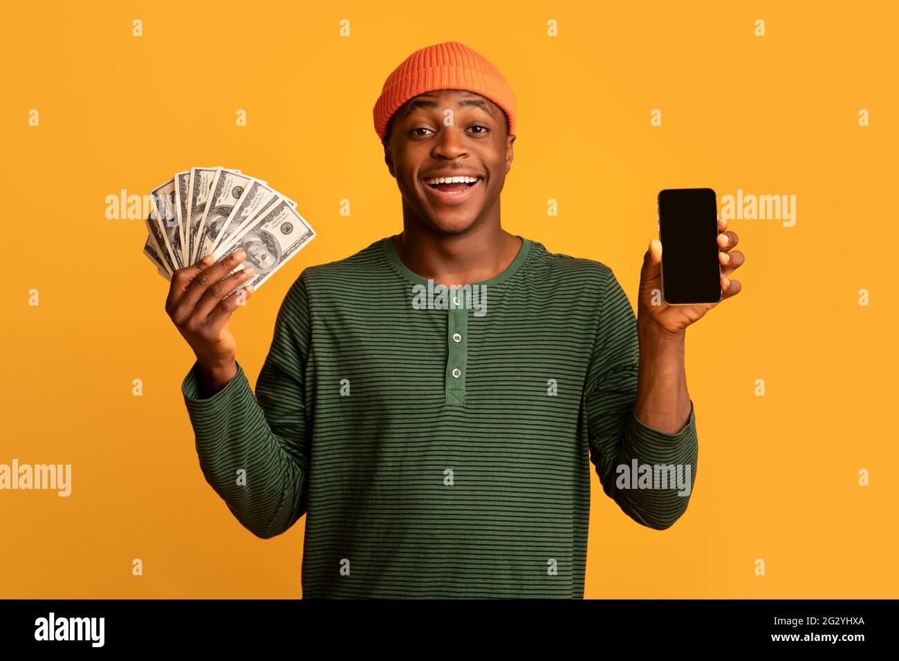 Cheerful Young Black Man Holding Smartphone With Blank Screen And Holding Cash Stock Photo