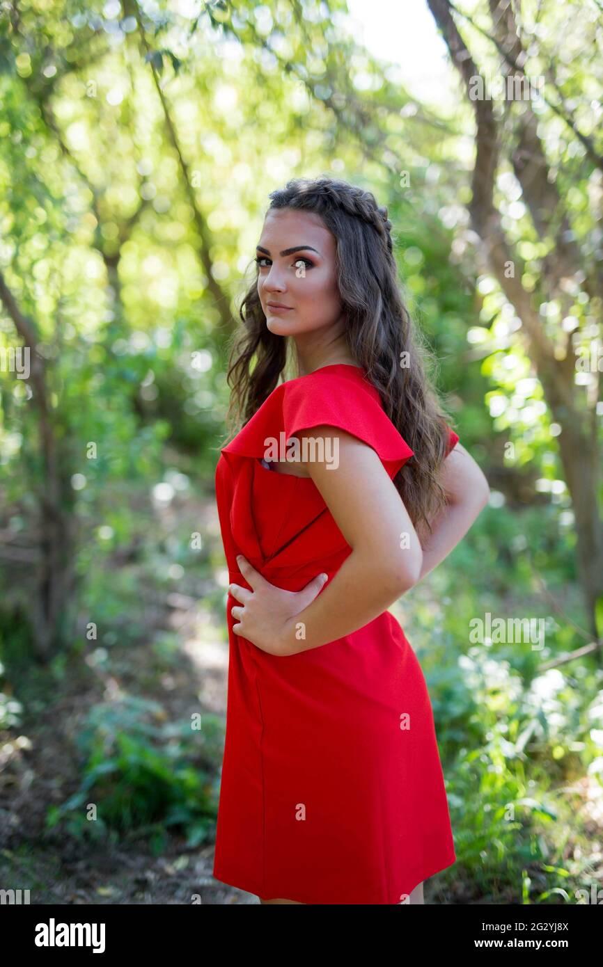 An attractive Caucasian female wearing a vibrant red dress posing in a ...