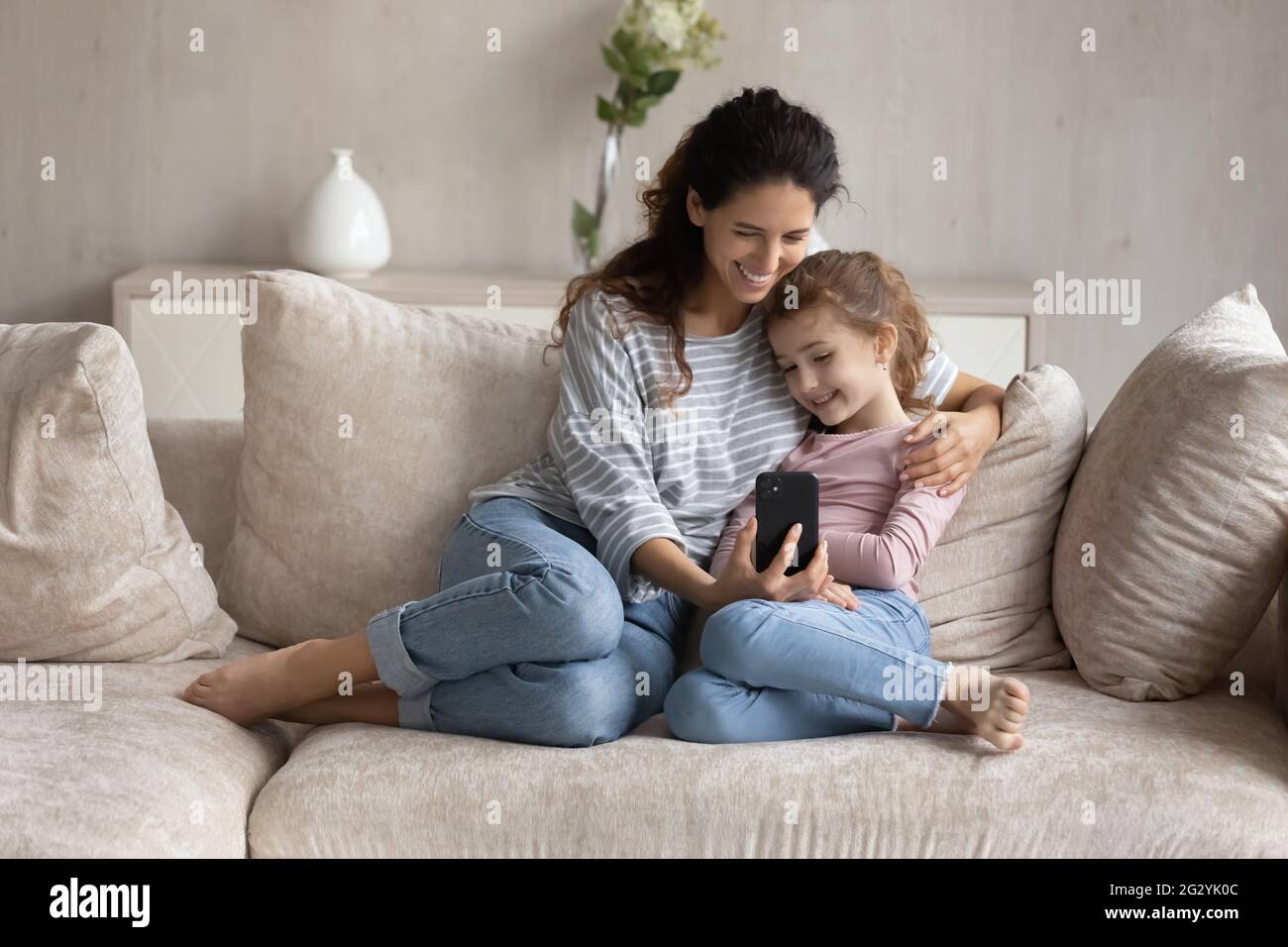 Happy Latin mom and biracial daughter talk on smartphone Stock Photo ...
