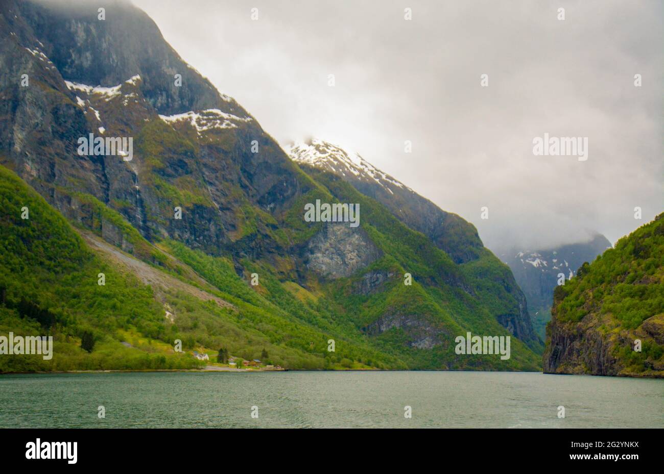 Large imposing mountains with snow capped peaks on either side of the fjord in Norway. Stock Photo