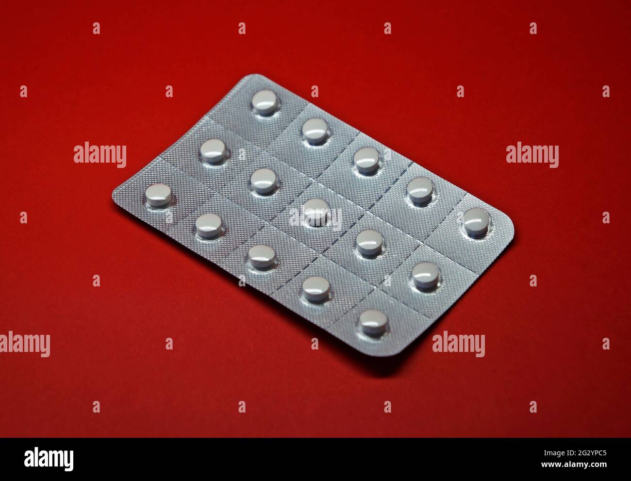 Blister pack of white pills on red background Stock Photo