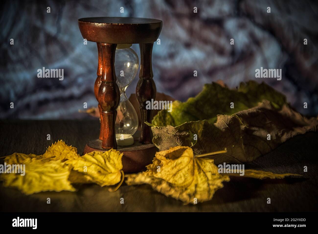 Autumn leaves and an hourglass on a table Stock Photo