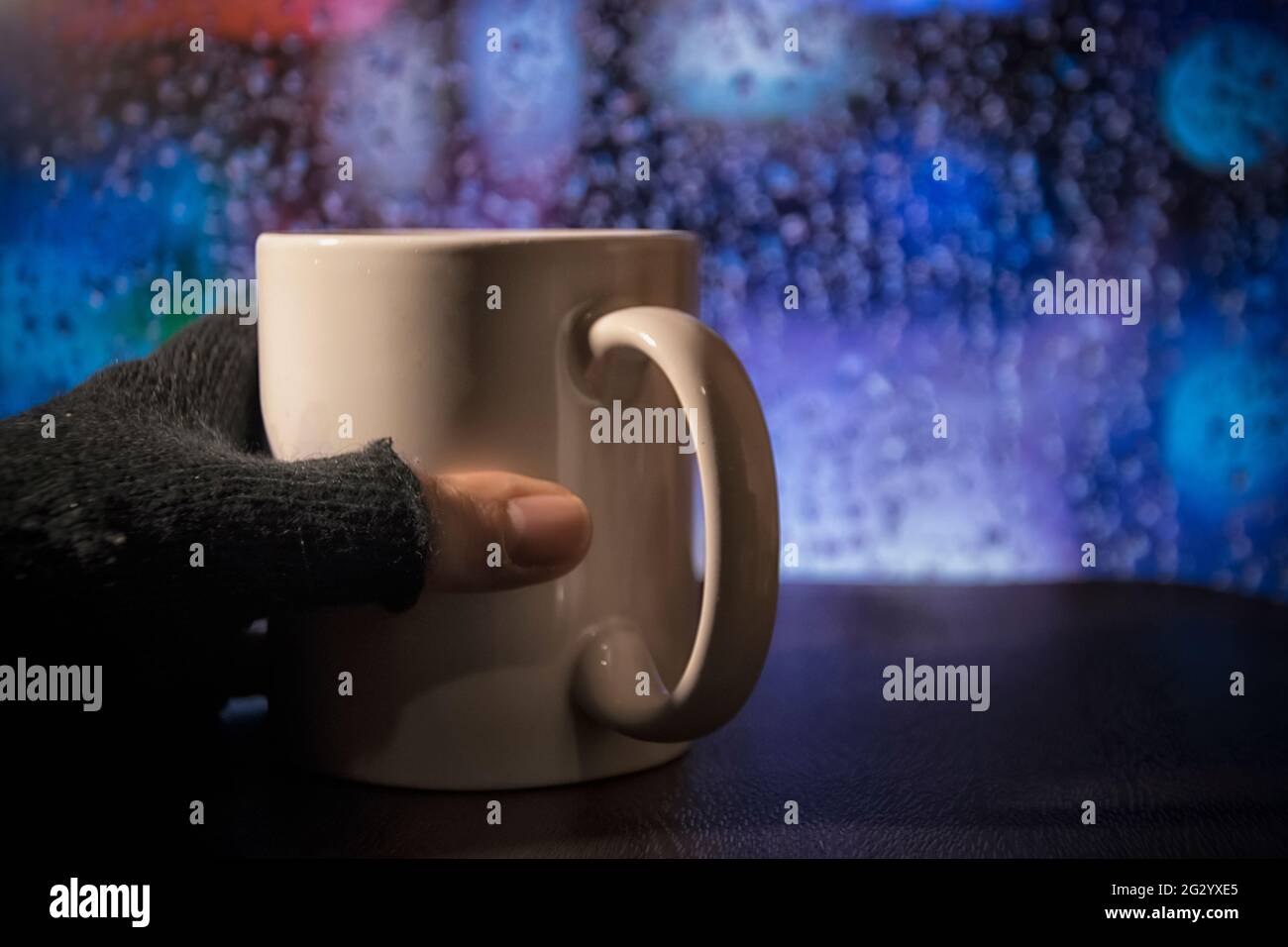 A hand with glove with a cup during the rain Stock Photo