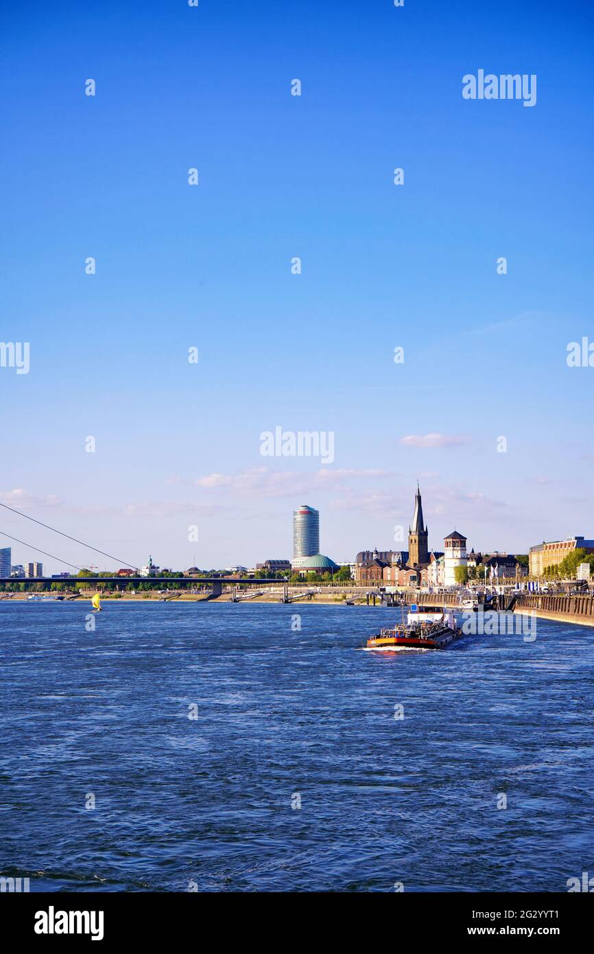 Rhine river skyline in Düsseldorf on a sunny day with blue sky. Oberkasseler bridge, Tonhalle, Lambertus church and Castle Tower in the background. Stock Photo