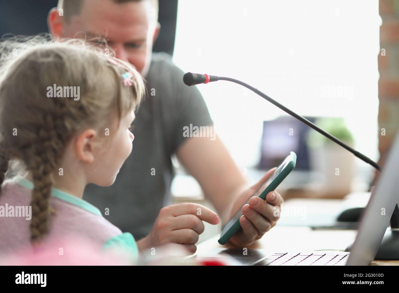 Male programmer shows little girl game on smartphone for testing Stock Photo