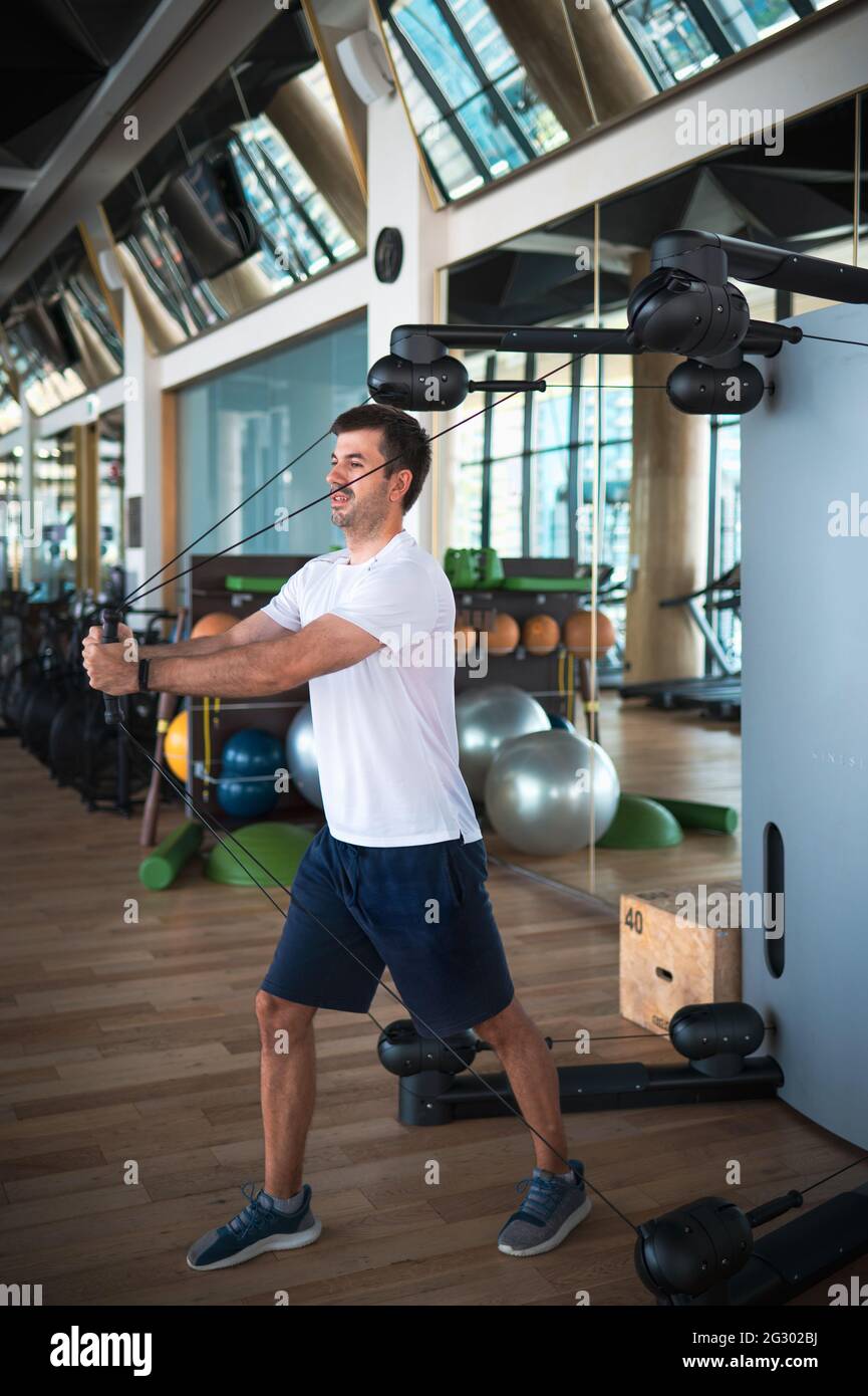 Man exercising in the gym on a pec deck machine for chest and pectoral muscles cable crossover workout Stock Photo Alamy