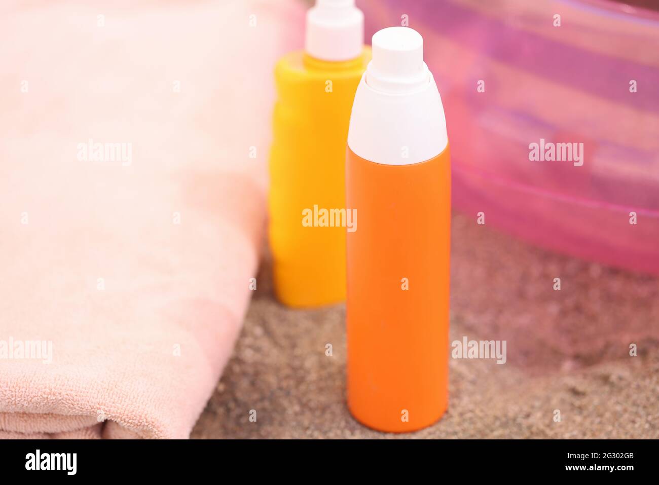 Two bottles of sunscreen stand on sand on beach Stock Photo