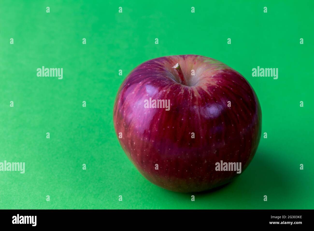 Red apple on green background with shadow and space for text Stock Photo