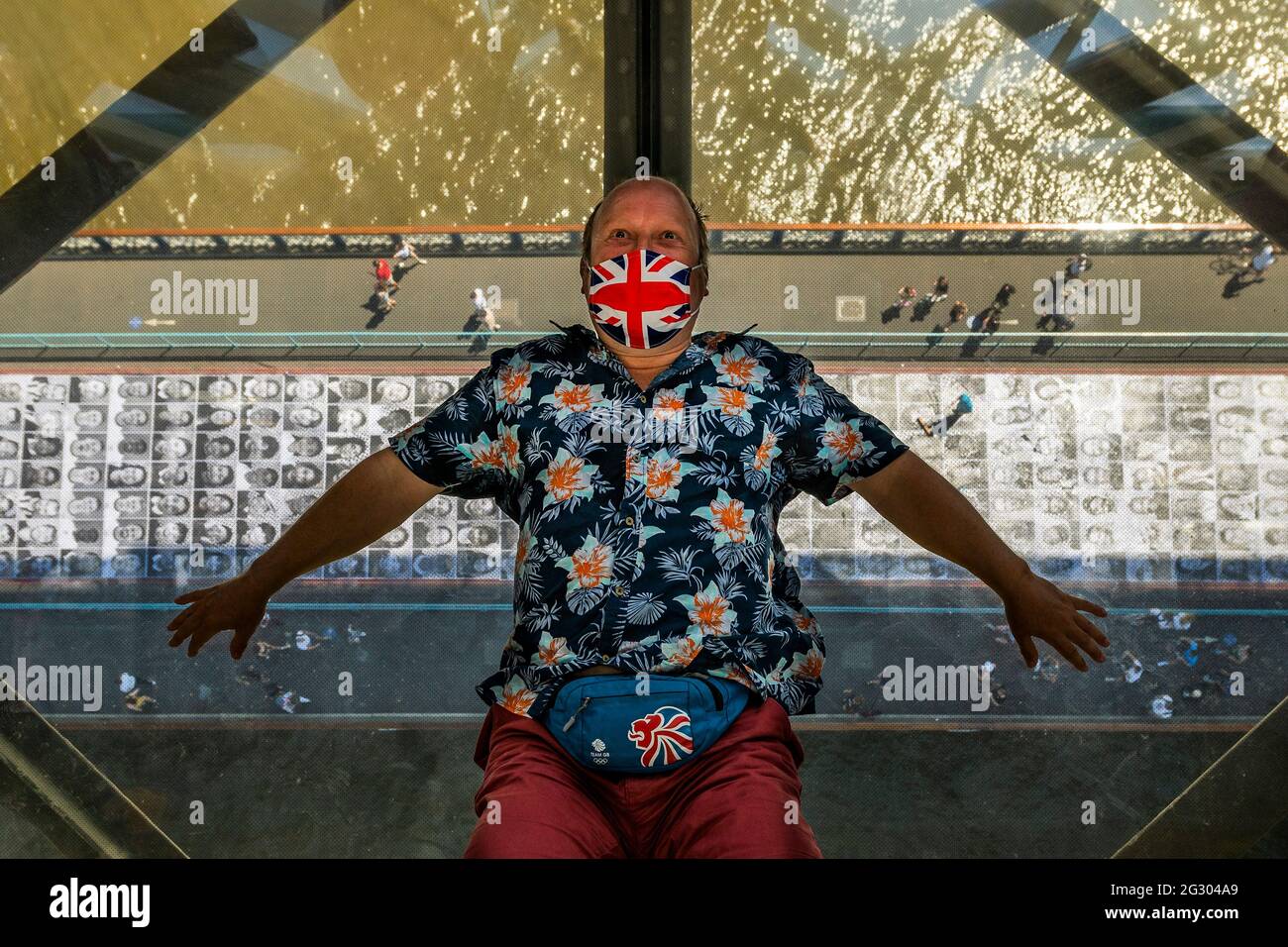 London, UK. 13 Jun 2021. Tourists lie on the floor of the viewing platform to look at themselves in the mirrored ceiling - Tower bridge as it is pasted with more than 3,000 black and white portrait photographs in celebration of the UEFA EURO 2020 Football Championships. Credit: Guy Bell/Alamy Live News Stock Photo