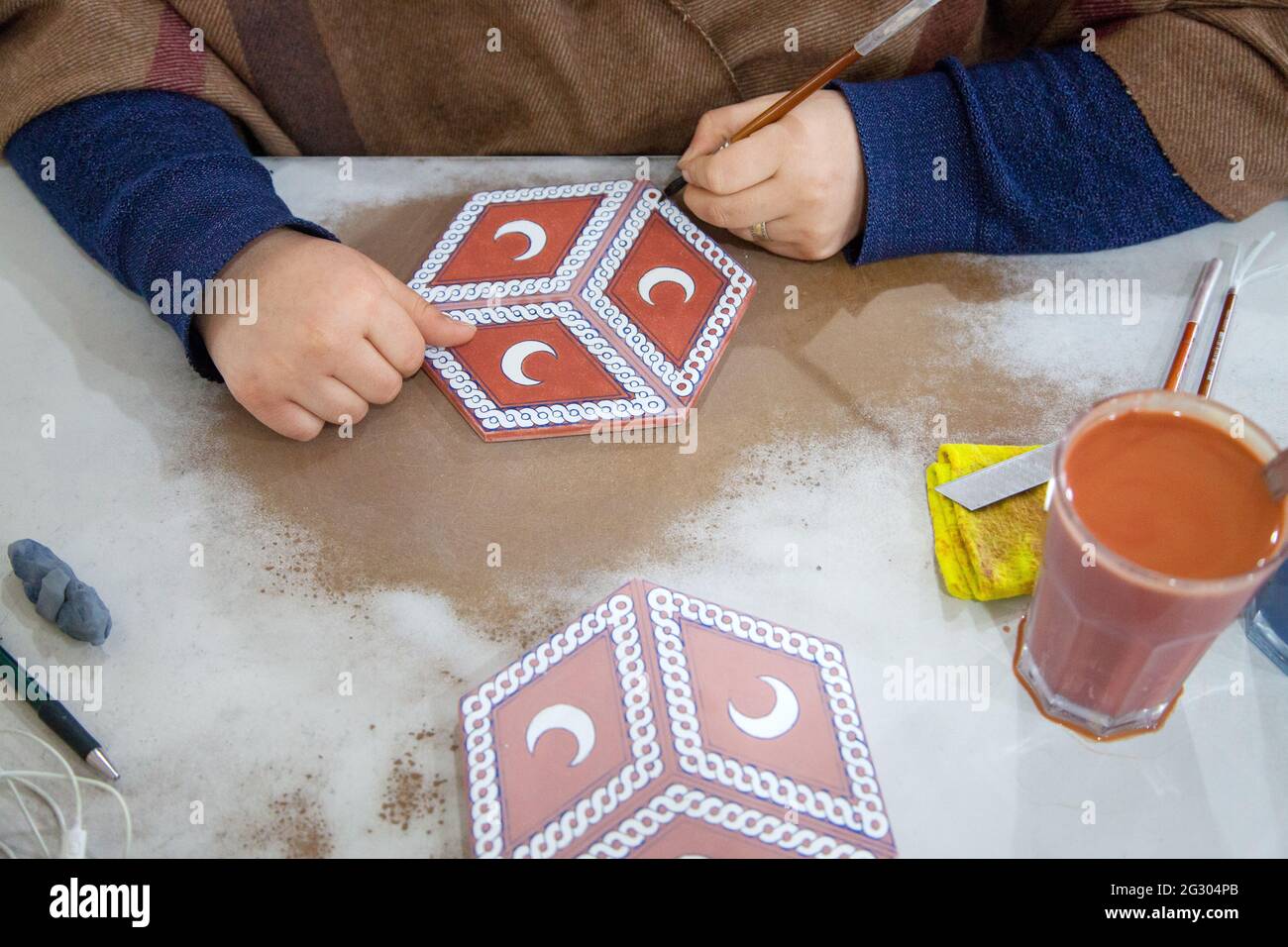 Cini art. Turkish tile art. Female tile artist paints porcelain at workshop. Iznik, Turkey - 12/29/2016 Stock Photo