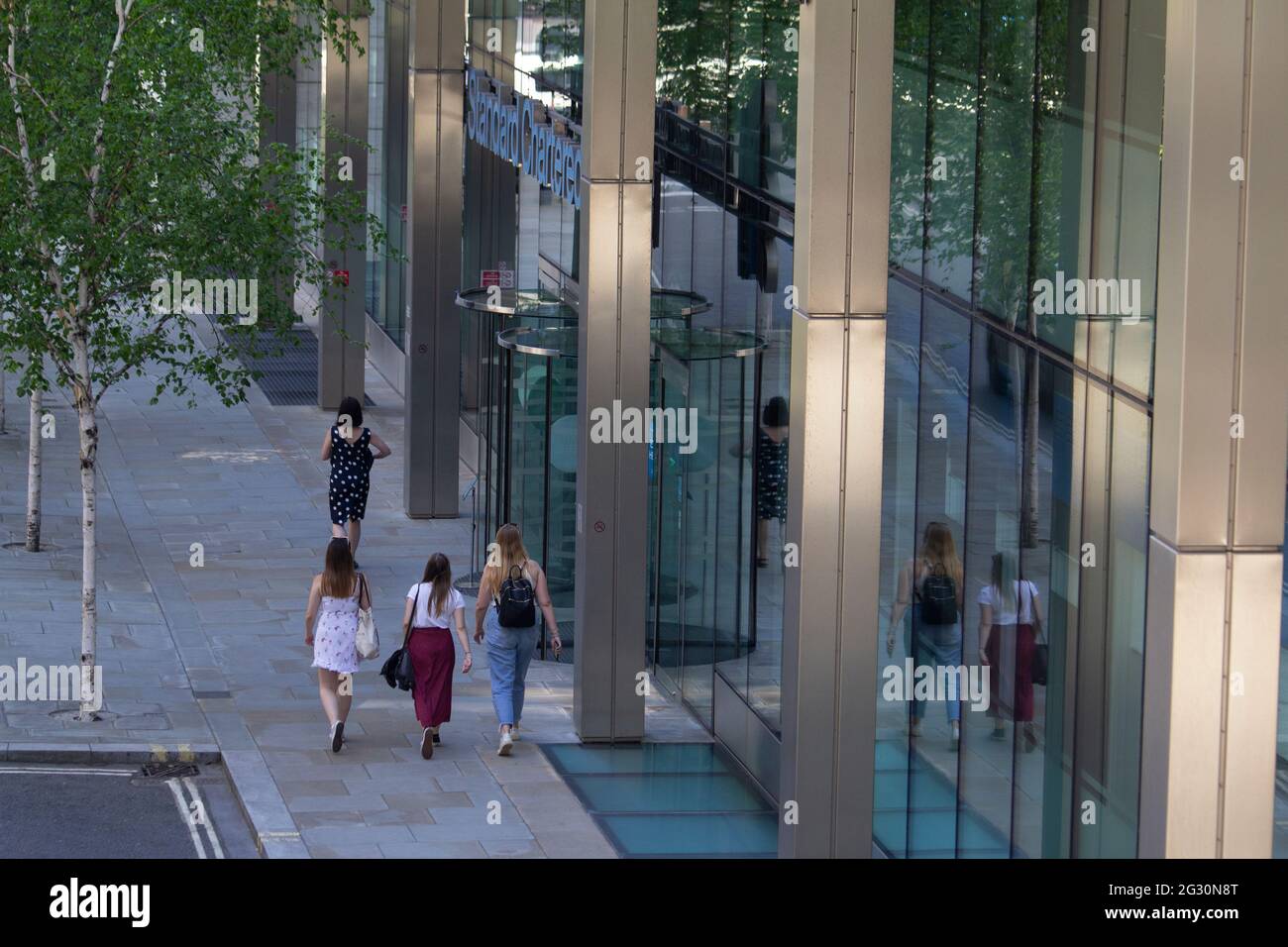 Female city workers walking past Standard Chartered bank in City of London Stock Photo