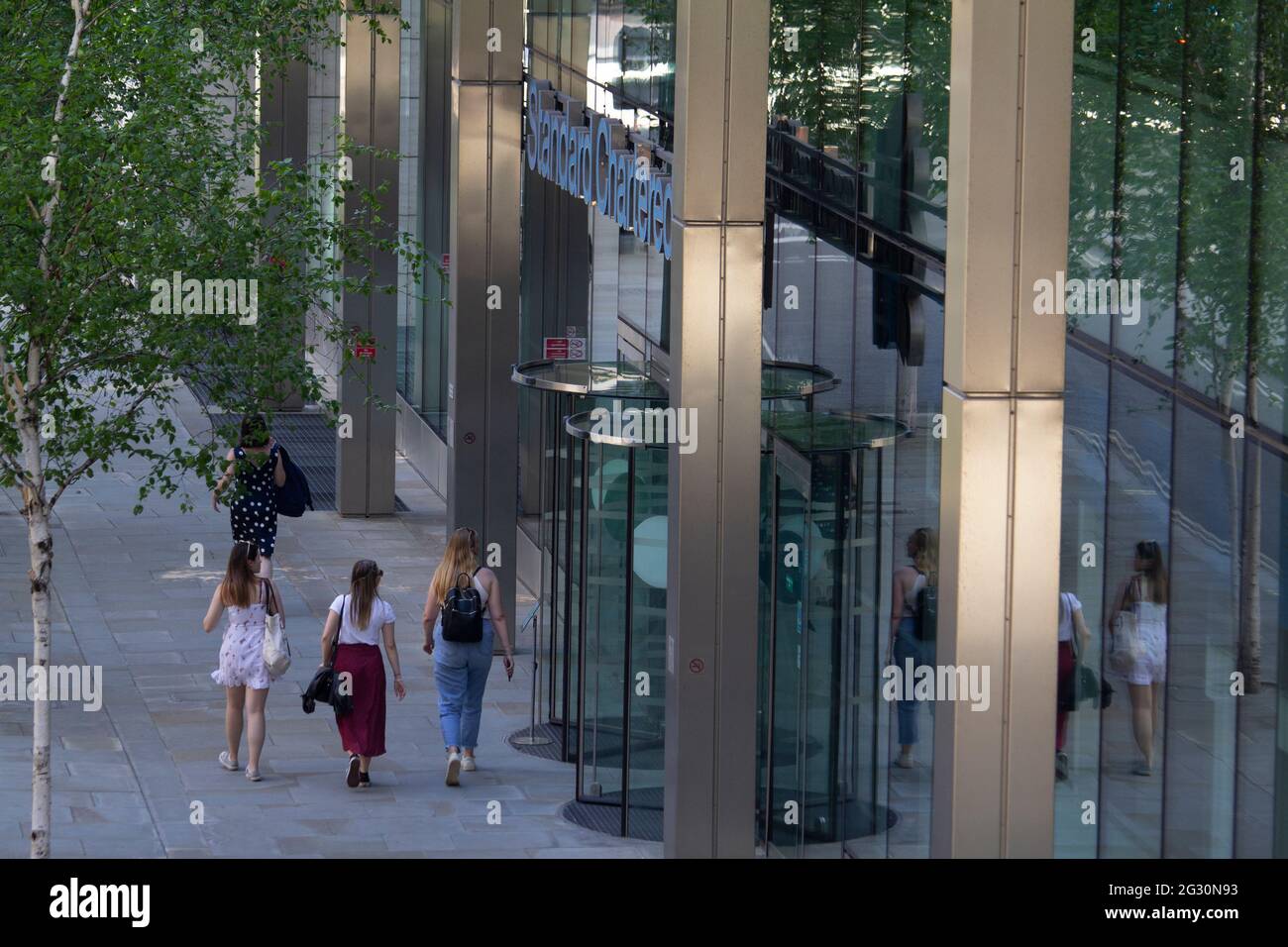 Female city workers walking past Standard Chartered bank in City of London Stock Photo