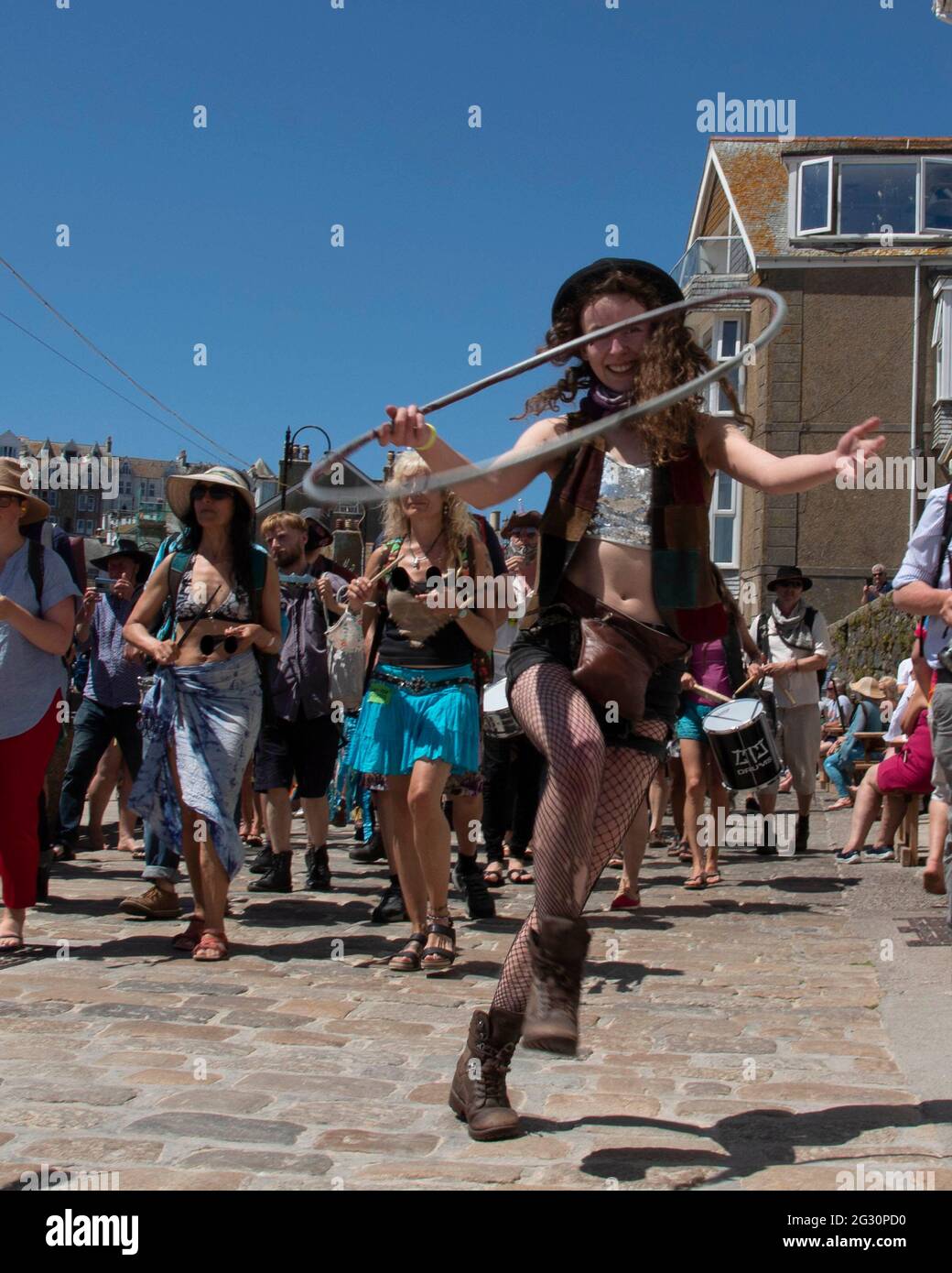 St Ives, Cornwall, UK. 13th June, 2021. An Extinction Rebellion samba band makes their way into St Ives harbour for the last day of the G7 summit in Crabis bay, just around the corner. The samba band is accompanied by a girl with a hula hoop, leading the group. Cornwall. 13the June 2021. Anna Hatfield/ Pathos Credit: One Up Top Editorial Images/Alamy Live News Stock Photo
