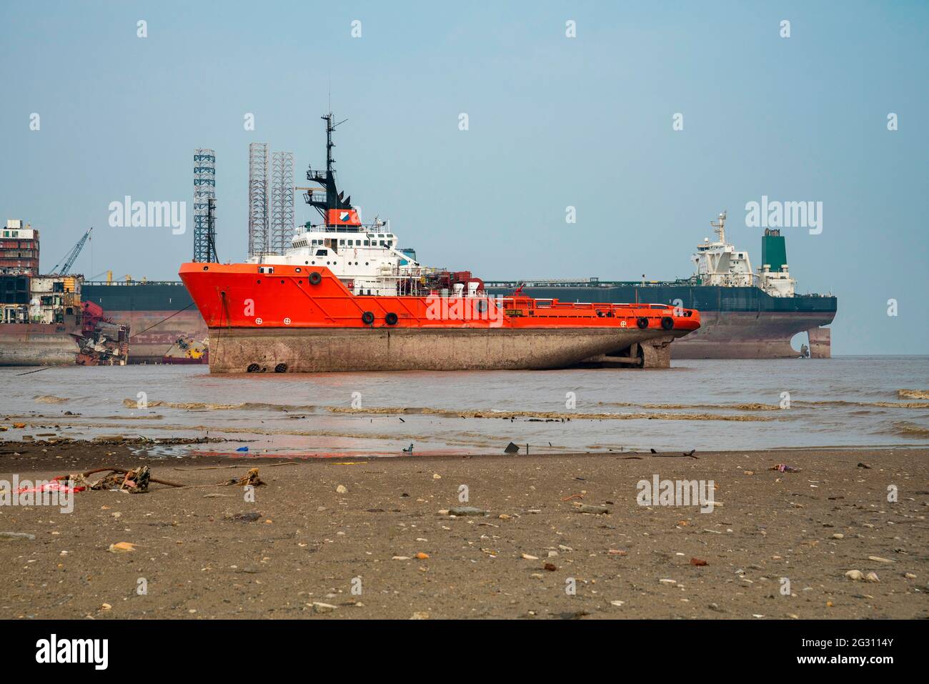 Alang ,01, February, 2016:Small red boat and large ship brought to Alang Ship Breaking Yard for scrapping and marine salvage Bhavnagar, Gujarat,India Stock Photo
