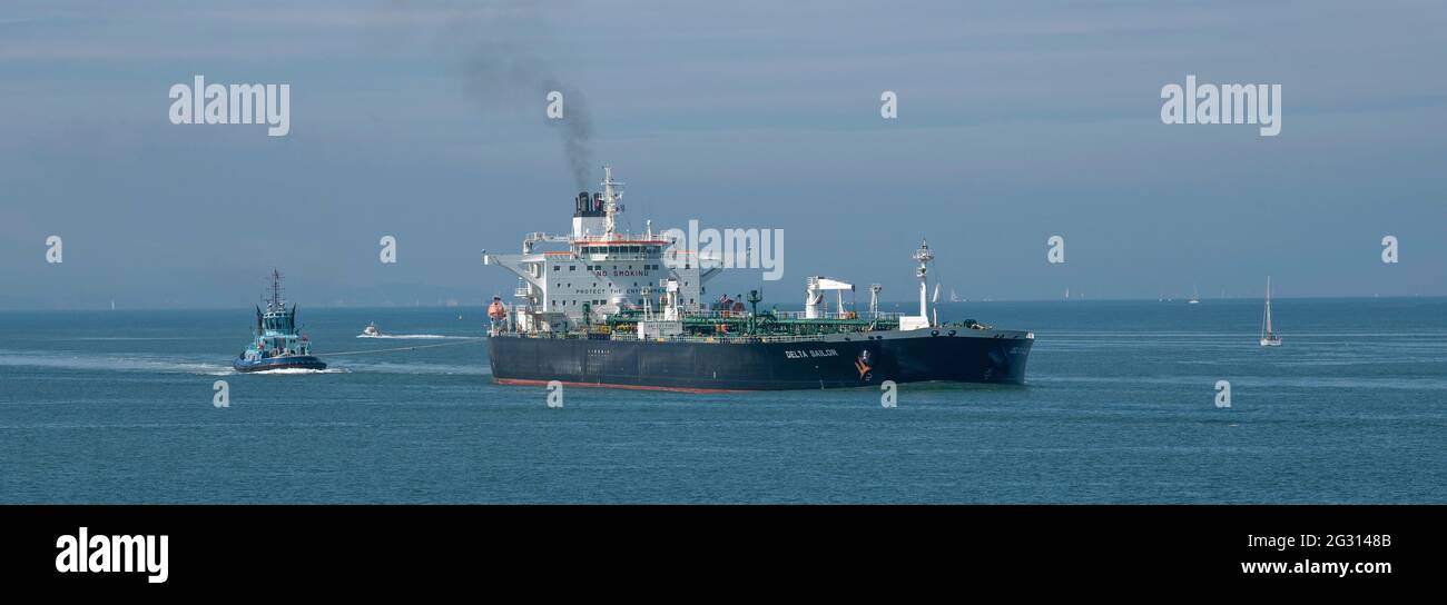 The Solent, Southampton, UK. 2021. Ocean going tug off the stern of a large crude oil tanker as it makes a turn onto Southampton Water, UK Stock Photo