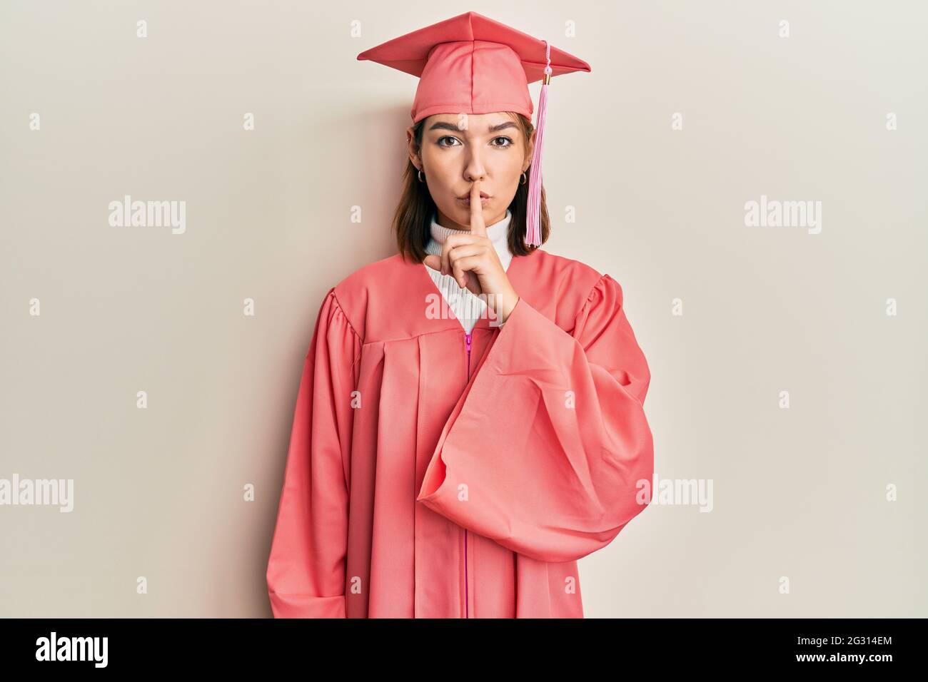 Young caucasian woman wearing graduation cap and ceremony robe asking ...