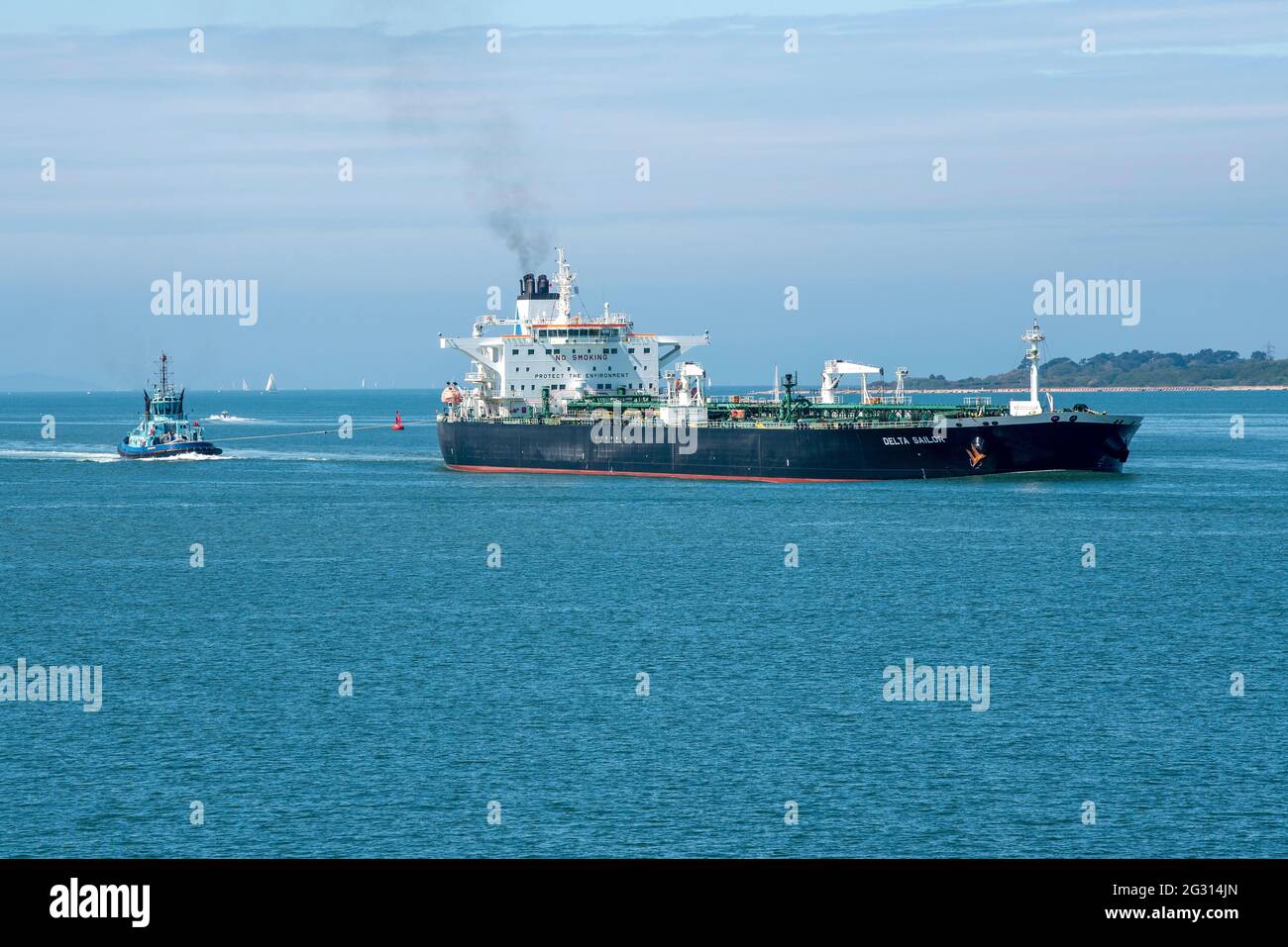 The Solent, Southampton, UK. 2021. Ocean going tug off the stern of a large crude oil tanker as it makes a turn onto Southampton Water, UK Stock Photo