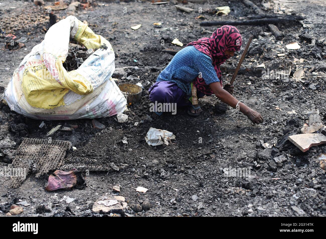 New Delhi, India. 13th June, 2021. A Rohingya refugee looks for her belongings amid the charred remains of their camp, during the aftermath.A fire incident broke out at the Rohingya refugee camp leaving over 50 shanties of Rohingya refugees gutted. The cause of the fire has not yet been established. Credit: SOPA Images Limited/Alamy Live News Stock Photo
