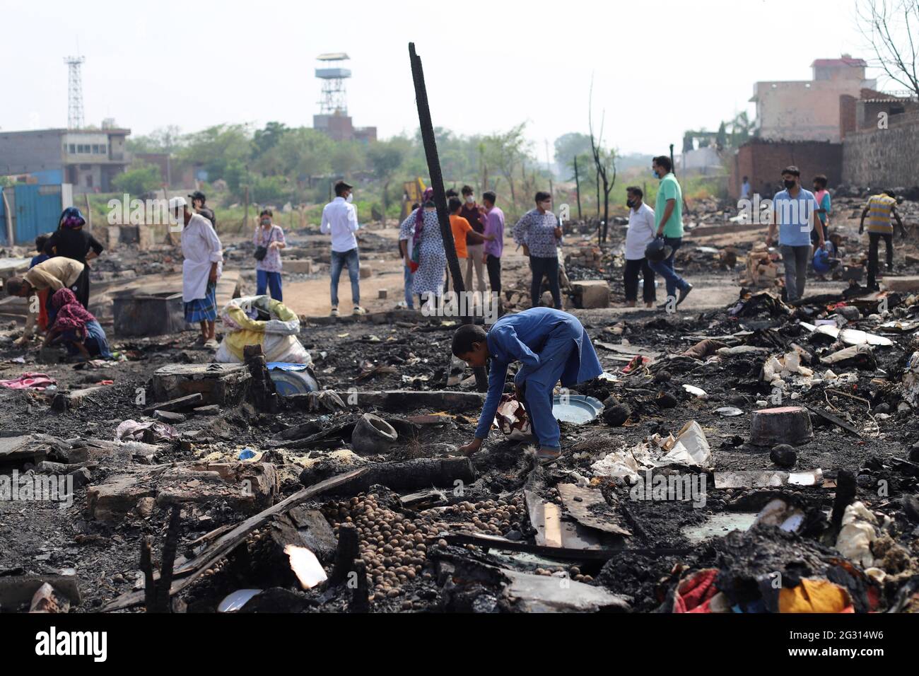 New Delhi, India. 13th June, 2021. Rohingya refugees look around the charred remains of their camp during the aftermath. A fire incident broke out at the Rohingya refugee camp leaving over 50 shanties of Rohingya refugees gutted. The cause of the fire has not yet been established. Credit: SOPA Images Limited/Alamy Live News Stock Photo