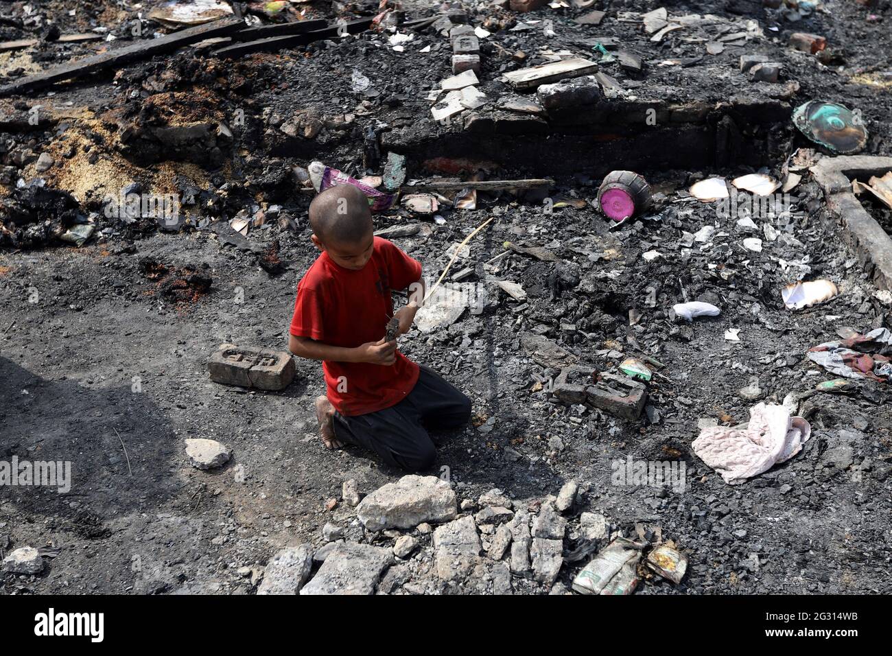 New Delhi, India. 13th June, 2021. A young boy is looking for his belongings from the charred remains of his camp, during the aftermath.A fire incident broke out at the Rohingya refugee camp leaving over 50 shanties of Rohingya refugees gutted. The cause of the fire has not yet been established. Credit: SOPA Images Limited/Alamy Live News Stock Photo
