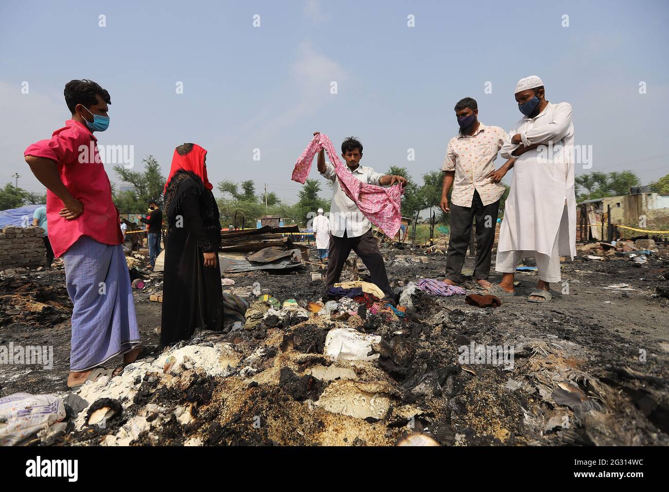 New Delhi, India. 13th June, 2021. Rohingya refugees look around in the charred remains of their camp, during the aftermath. A fire incident broke out at the Rohingya refugee camp leaving over 50 shanties of Rohingya refugees gutted. The cause of the fire has not yet been established. Credit: SOPA Images Limited/Alamy Live News Stock Photo