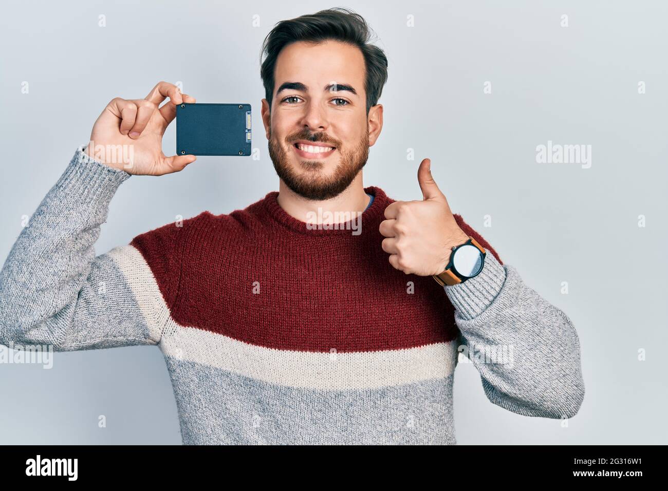 Handsome caucasian man with beard holding ssd memory smiling happy and ...