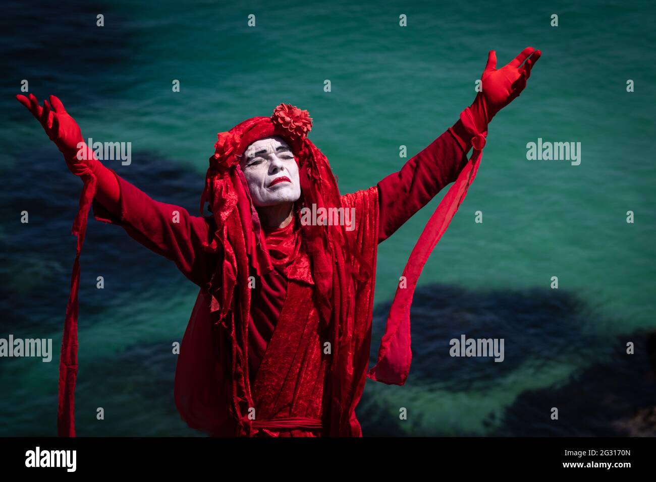 St Ives, UK. 13th June, 2021. The Red Rebel Brigade which is part of the Extinction Rebellion movement pose on St Ives Head. Extinction Rebellion take action for the third and final day of the G7 Summit. Credit: Andy Barton/Alamy Live News Stock Photo