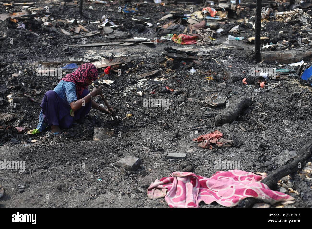 New Delhi, India. 13th June, 2021. A woman looks in the charred remains of their camp, during the aftermath.A fire incident broke out at the Rohingya refugee camp leaving over 50 shanties of Rohingya refugees gutted. The cause of the fire has not yet been established. (Photo by Amarjeet Kumar Singh/SOPA Imag/Sipa USA) Credit: Sipa USA/Alamy Live News Stock Photo