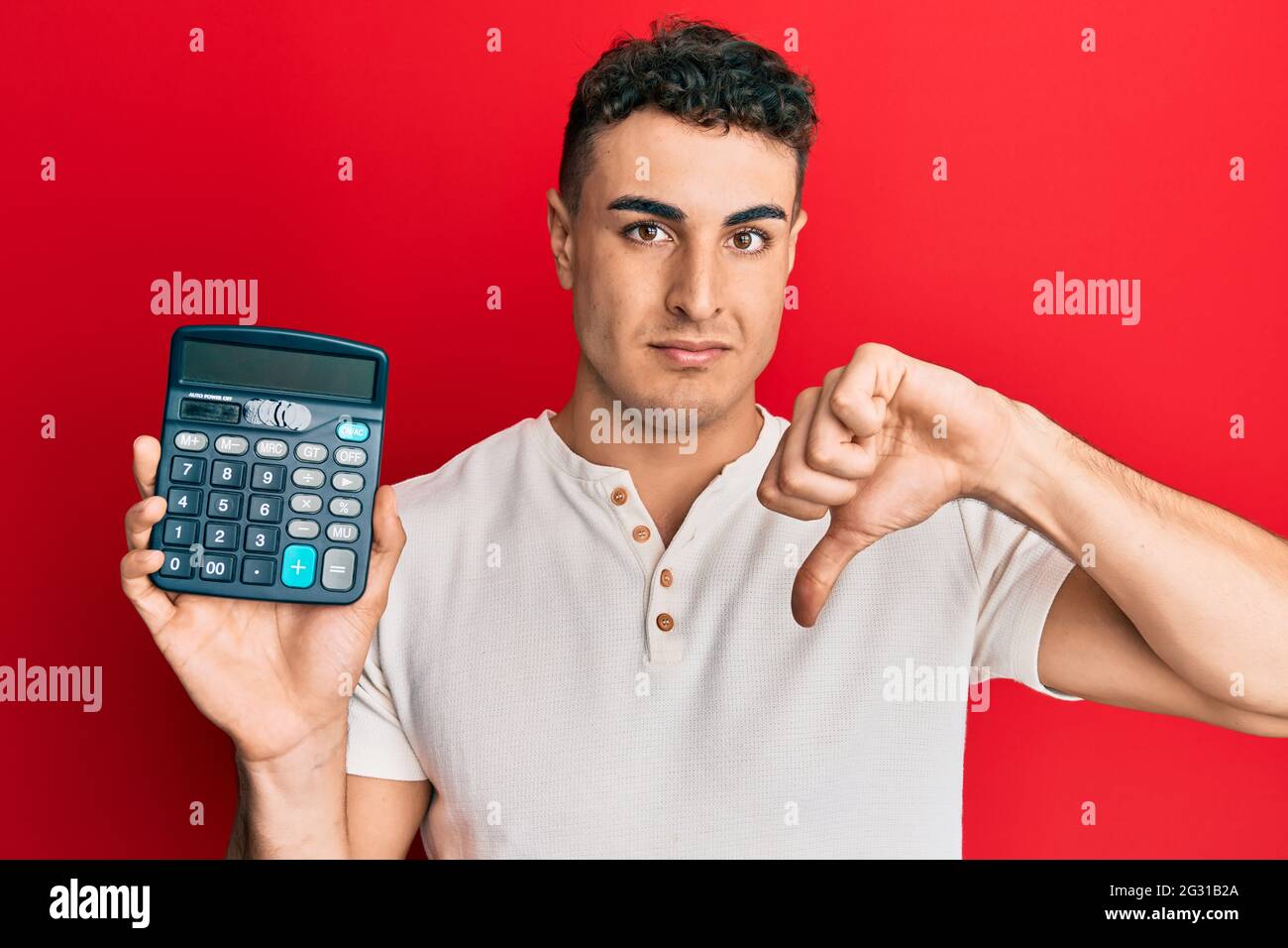 Hispanic young man showing calculator device with angry face, negative