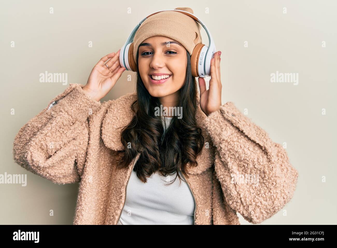 Young hispanic woman listening to music using headphones smiling with a ...