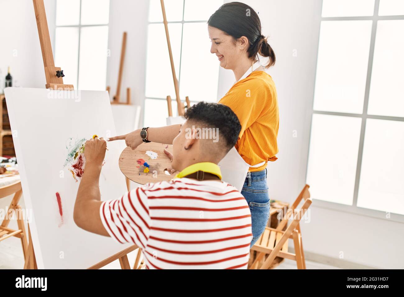 Student and teacher smiling happy painting at art school Stock Photo ...