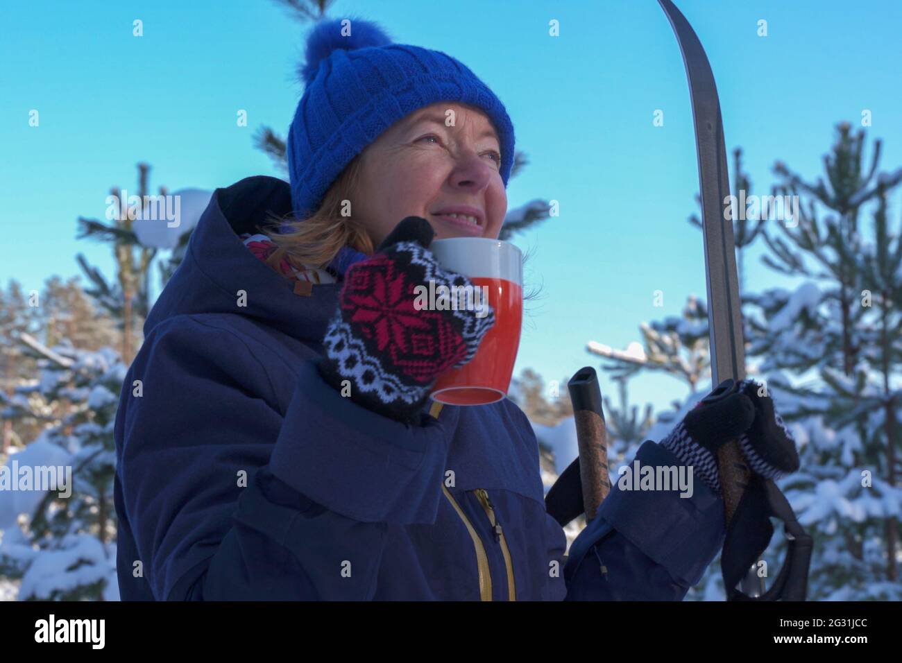 Close up view fit retired baby boomer senior woman after skiing winter sport exercise in woodland at snowy winter day. Active lifestyle in senior age Stock Photo