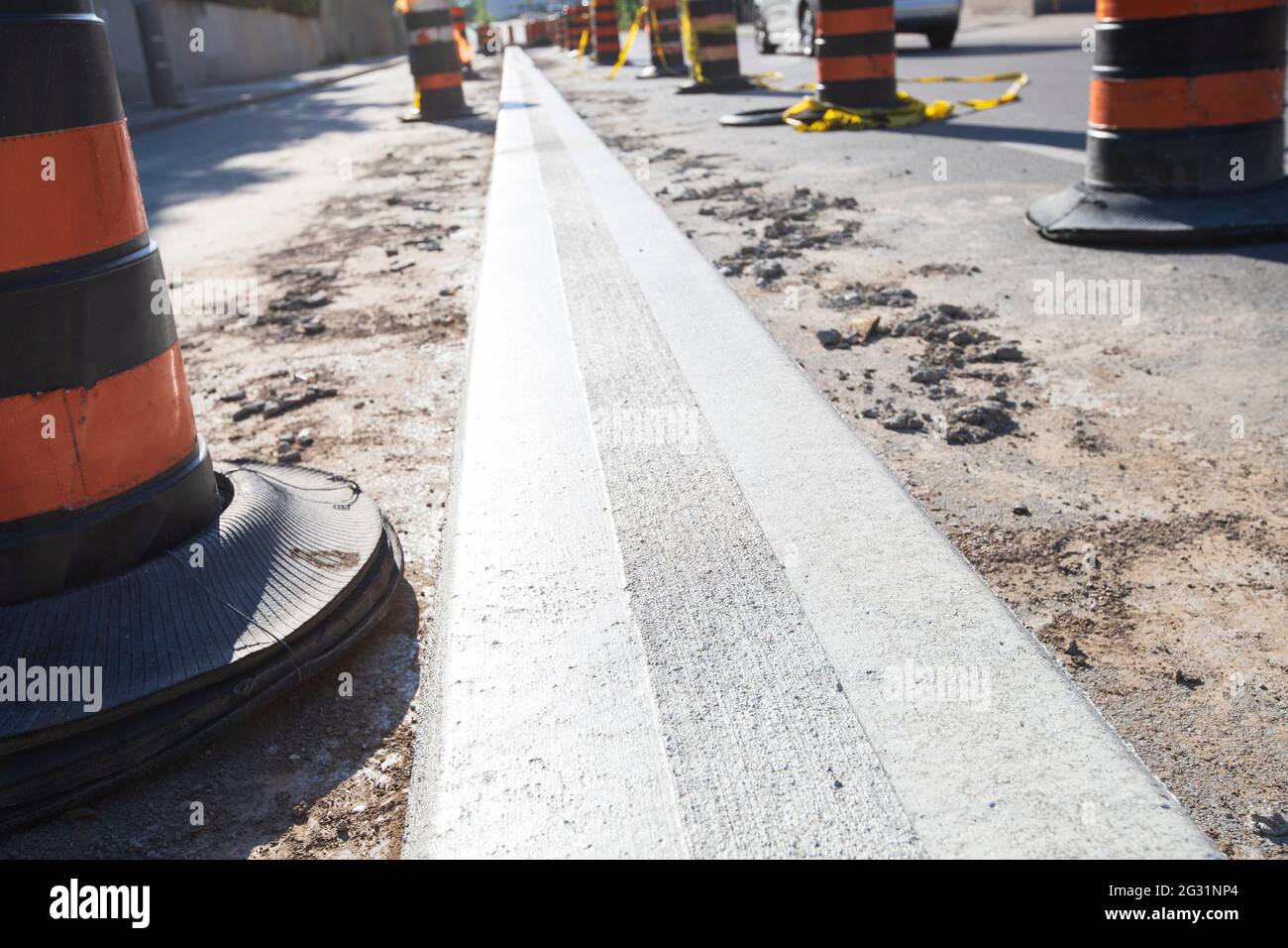 Freshly constructed concrete median strip in the street surrounded by safety cones. Stock Photo