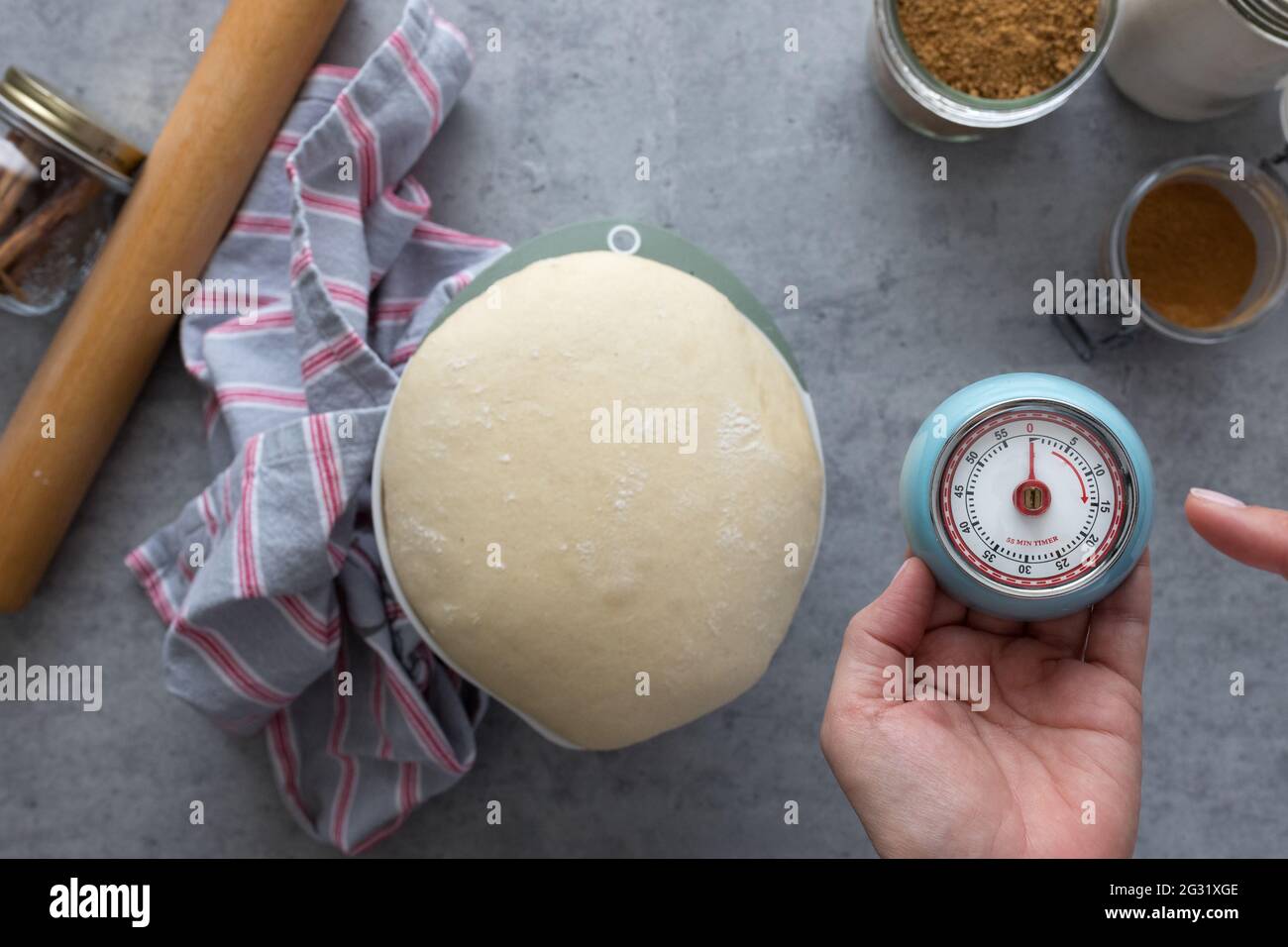 Woman hand holding an analog timer that indicates the dough is ready to be handled. Stock Photo