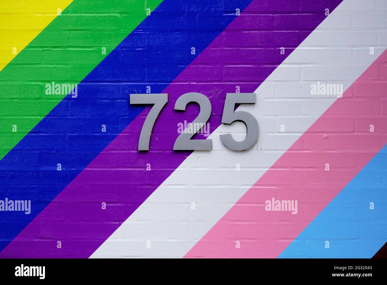 Colourful painted wall with bold diagonal lines in honour of Pride month with street number in centre Stock Photo
