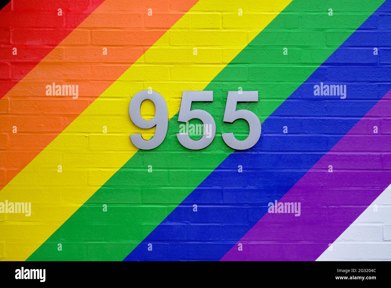 Colourful painted wall with bold diagonal lines in honour of Pride month with street number in centre Stock Photo
