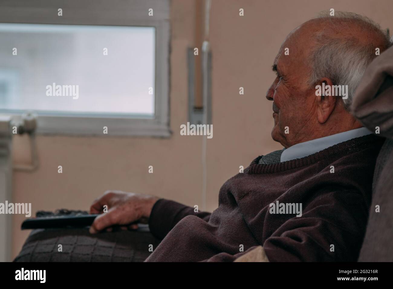 old man at home with the television remote Stock Photo