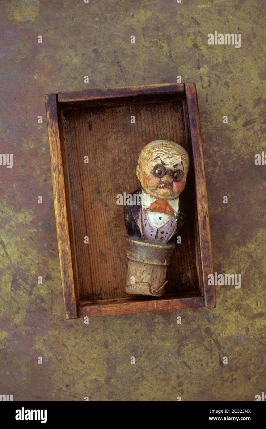 Old wooden box containing vintage wine bottle cork stopper with carved model of superior waiter or sommelier Stock Photo