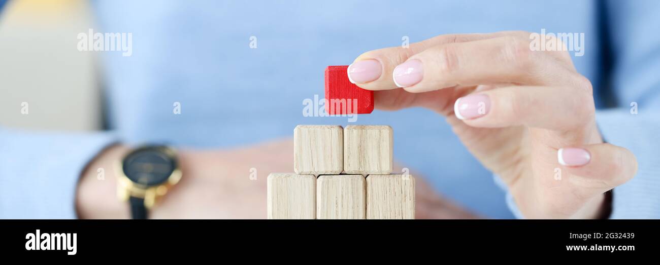 Woman building pyramid from wooden cubes closeup Stock Photo