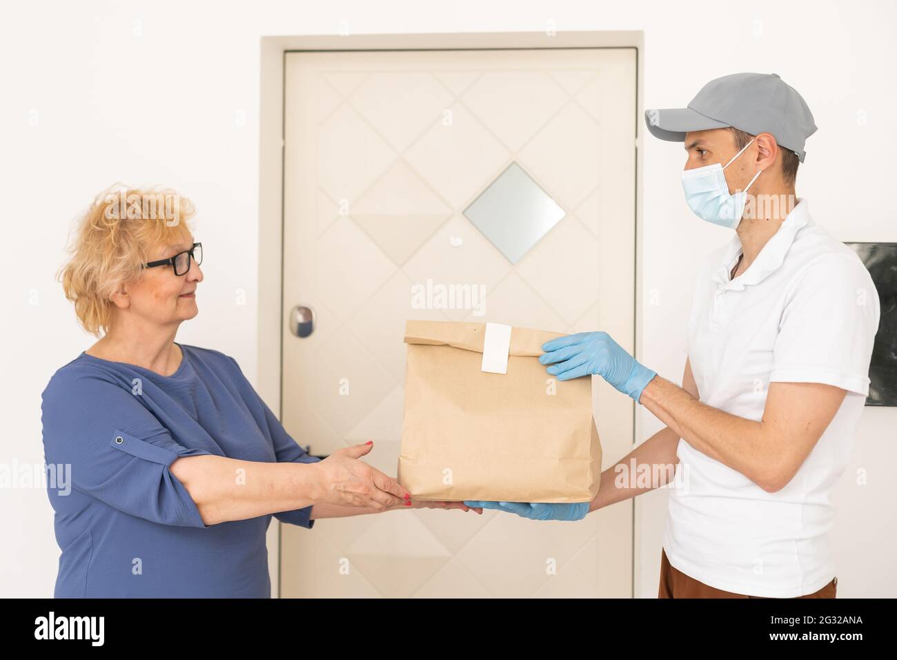 Courier of food delivery company giving products to elderly woman