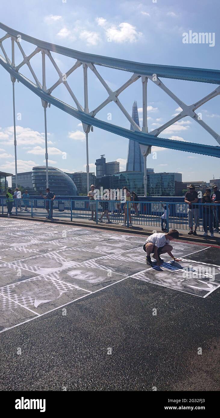 Tower Bridge, London, 13th July 2021. Inside Out Project outdoor art exhibition showing portraits of Londoners pasted onto the road on Tower Bridge. Stock Photo