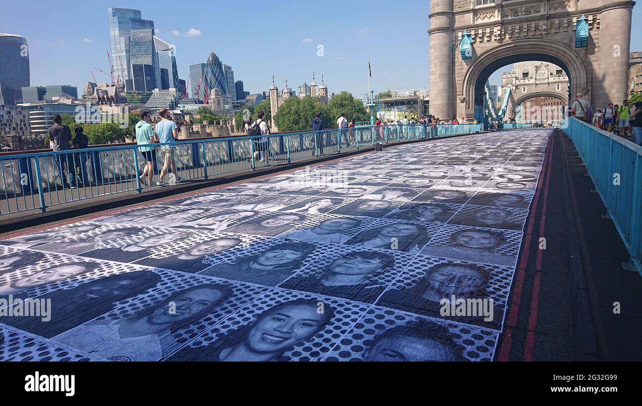 Tower Bridge, London, 13th July 2021. Inside Out Project outdoor art exhibition showing portraits of Londoners pasted onto the road on Tower Bridge. Stock Photo