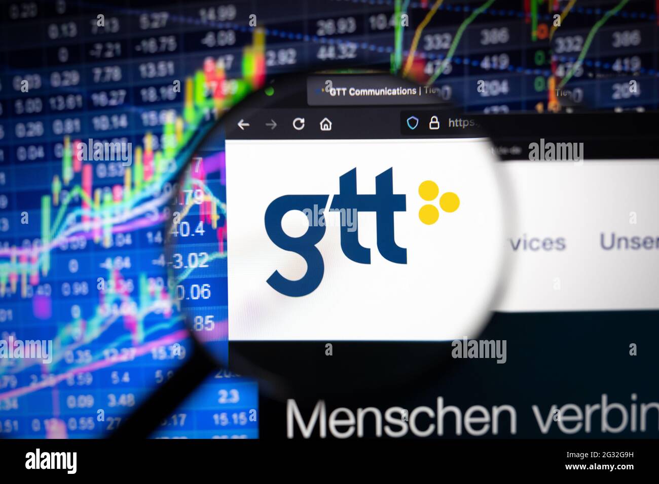 GTT company logo on a website with blurry stock market developments in the background, seen on a computer screen through a magnifying glass Stock Photo