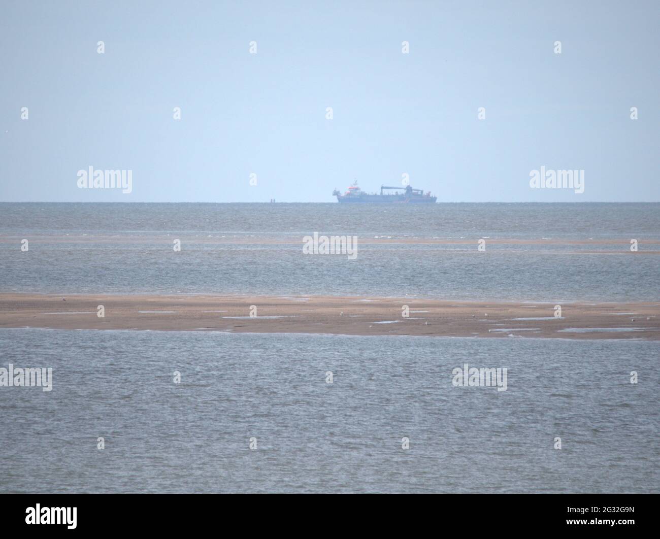 Unknown Vessel out on the horizon, avoiding the sand banks in the Irish Sea Stock Photo
