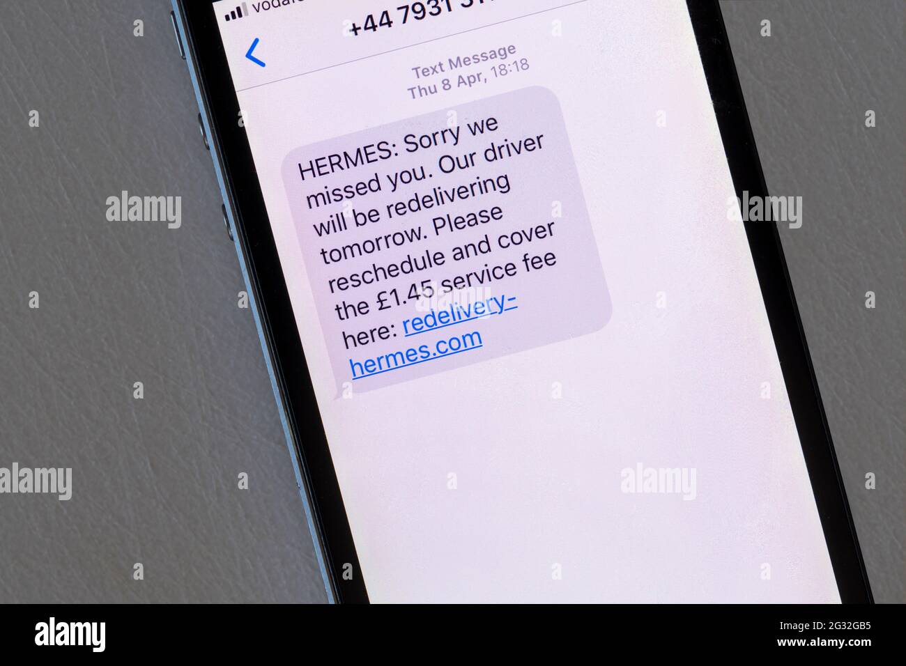 A scam message displayed on an iphone that pretends to be from a delivery company, asking for a service fee. Stock Photo
